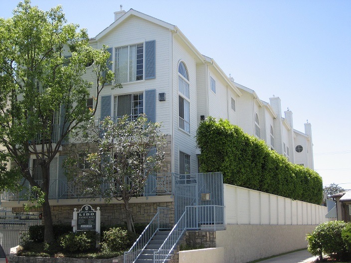 A white building with a green hedge on the side.